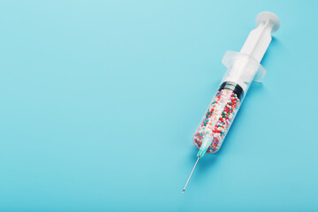 Syringe filled with colorful nano balls on a light blue background.