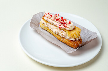 Eclair with cream and strawberries. On a white plate High quality photo