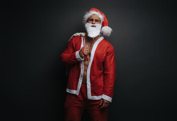 Fototapeta na wymiar Santa Claus with gift bag in studio. Muscular man in Christmas costume at grey background. Sexy handsome guy in red outfit.