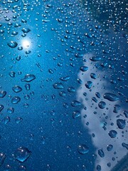 Water droplets on clean car close up with reflection of the sky