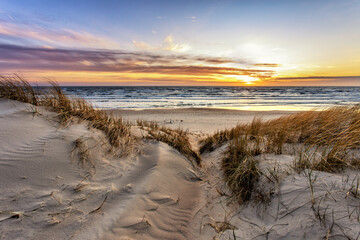 Sunset surrounded by dunes by the sea
