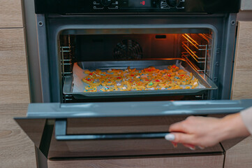 The girl opens the oven with cookies.