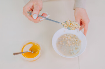 Mom prepares oatmeal with honey in the kitchen.