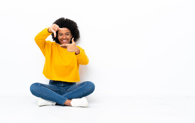 Young African American woman sitting on the floor focusing face. Framing symbol
