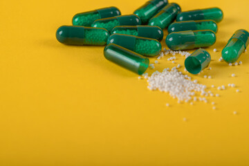 green capsule pills on yellow background. Antibiotics drug resistance. Antimicrobial capsule pills. Pharmaceutical industry. Healthcare and drugstore. Pharmaceutics concept. Drug in hospital. 