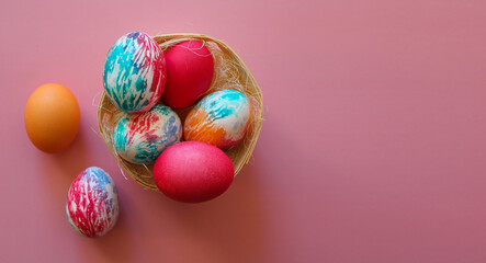 Happy Easter holiday! Colorful hand-painted Easter eggs in a decorative nest on pink background.