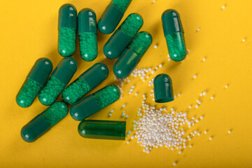 green capsule pills on yellow background. Antibiotics drug resistance. Antimicrobial capsule pills. Pharmaceutical industry. Healthcare and drugstore. Pharmaceutics concept. Drug in hospital. 