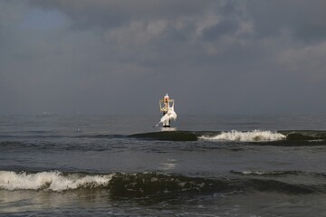Sea with waves in cloudy and sunny winter day. Frozen lantern covered ice in middle of sea.