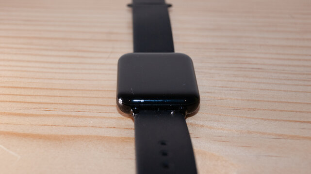 Reloj con car&aacute;tula y correa negra sobre mesa de madera