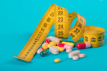 Diet concept. Slim by pills, dangerous for health. Centimeter tape and pills on a colored background with space for text. concept of losing weight, diet, fat burning, healthy eating. minimalism.