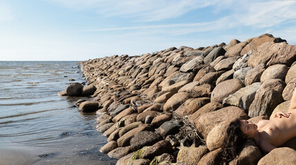 Nude woman posing on a stone pier
