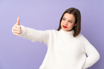 Teenager girl isolated on purple background giving a thumbs up gesture