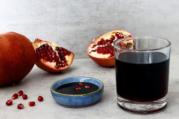 Pomegranate molasses in small bowl and juice in glass. Pomegranate sweet and sour syrup with...