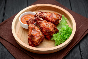 BBQ chicken wings with spicy sauce on a wooden plate