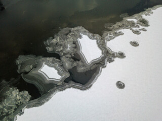 Aerial drone top view. Frosty pattern drawing on the river. Cloudy frosty winter morning.