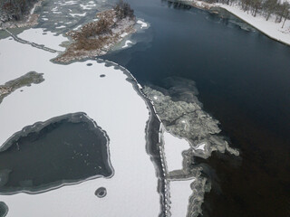 Aerial drone top view. Frosty pattern drawing on the river. Cloudy frosty winter morning.