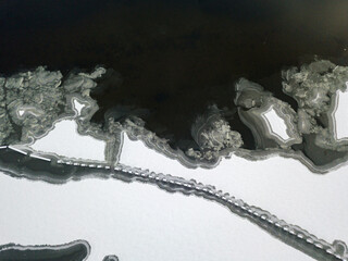 Aerial drone top view. Frosty pattern drawing on the river. Cloudy frosty winter morning.