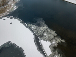 Aerial drone top view. Frosty pattern drawing on the river. Cloudy frosty winter morning.
