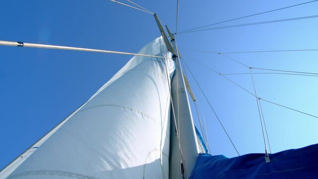 Nautical vessel. A sailboat mast and jib seen from below. 4k slow motion