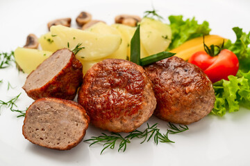 Homemade cutlets with potatoes and vegetables on a white background.