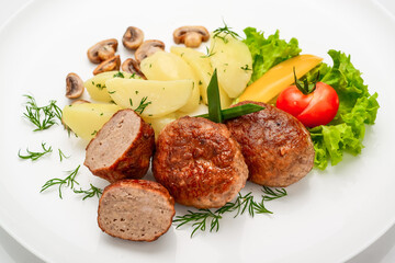 Homemade cutlets with potatoes and vegetables on a white background.