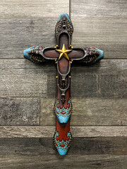Decorative Christian cross made of Cowboy boots hanged on wall