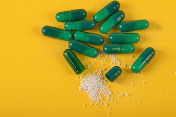 green capsule pills on yellow background. Antibiotics drug resistance. Antimicrobial capsule pills. Pharmaceutical industry. Healthcare and drugstore. Pharmaceutics concept. Drug in hospital. 