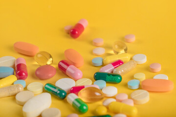 Assorted pharmaceutical medicine pills, tablets and capsules over yellow background. High number of pills on  surface. High resolution image for pharmaceutical industry.