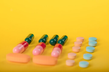 Assorted pharmaceutical medicine pills, tablets and capsules over yellow background. High number of pills on  surface. High resolution image for pharmaceutical industry.