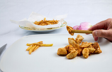 Small pieces of fried chicken, French fries and a wooden clothespin