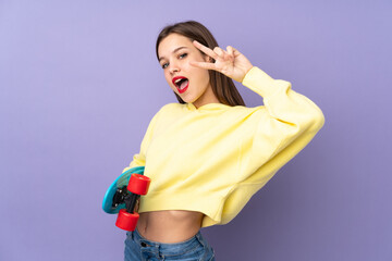 Teenager girl isolated on purple background with a skate with happy expression © luismolinero