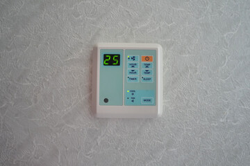 The air conditioner control panel is installed on the wall and the temperature is set at 25 degrees...
