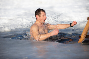 A man plunges into an ice-hole during the winter festival of the baptism of Jesus. A man swims in the ice-hole in winter. Walrus people.