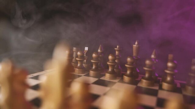 Close up of white chess pieces on board with dissipating steam. Two rows of wooden figures on chessboard on black background. Concept of intelligent, logical and strategic game.