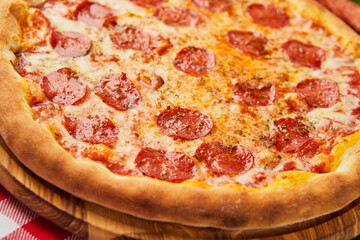 Traditional italian Pizza Pepperoni with salami, mozzarella and basil on green grass background