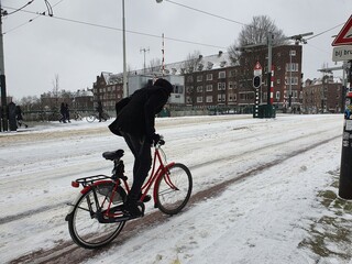 Snowy Bridge in Amsterdam with a Young Man in Black Clothes on a Red Bicycle