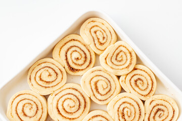 Uncooked cinnamon and cinnamon buns in a baking dish ready to bake.
