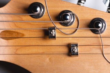 Guitar fretboard with tuning pegs and strings on a gray background. Close-up