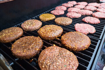 Hamburger patties grilling outdoors on a gas barbecue grill