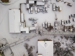 Snow-covered industrial parking. Aerial drone view. Winter snowy evening.