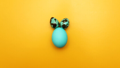 An Easter egg painted blue on a yellow background. View of the Easter bunny.