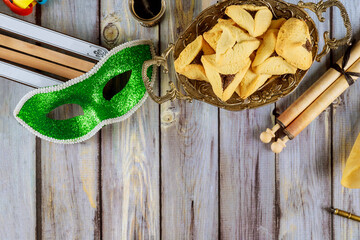 Jewish carnival Purim celebration on hamantaschen cookies, noisemaker and mask with parchment