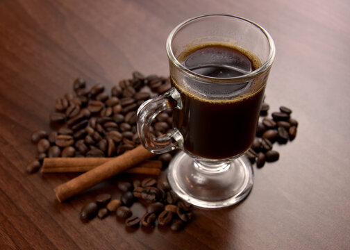 Cup of coffee on the table stock images. Cup of black hot coffee with coffee beans and cinnamon stock images. Coffee in a small glass cup stock photo