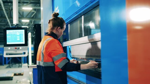 Female worker bending aluminum plate using a modern machine
