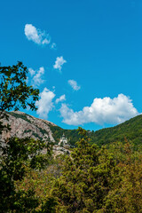 Summer sunny view of the Crimean road in the mountains. Beautiful mountain landscape of the Crimean Peninsula. In the distance, the Church of the Resurrection of Christ in Foros