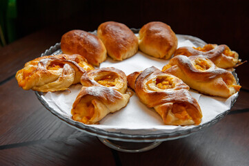 Apricot Danish pastries on a white napkin. The cakes are served in a tall glass vase. Close-up, selective focus