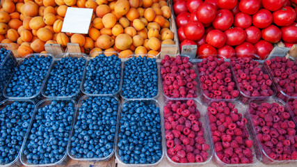 Blueberries, raspberries and blackberries are sold at the market. There are containers of berries on the counter