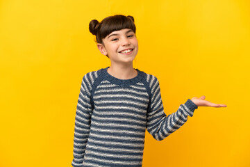 Little caucasian girl isolated on yellow background holding copyspace imaginary on the palm to insert an ad