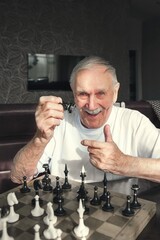 Portrait of a happy elderly man playing chess. man rejoices in victory