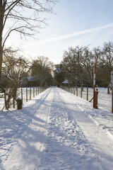 Weg mit Schranke und Schneespuren und Häusern